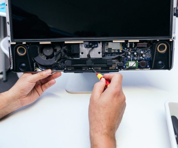 Hands fixing a laptop, showcasing internal components.
