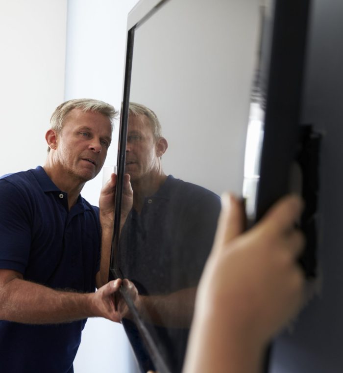 Two Men Fitting Flat Screen Television To Wall